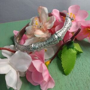 Silver tone bangle bracelet with clasp and lock. Oval. A few tiny diamonds.